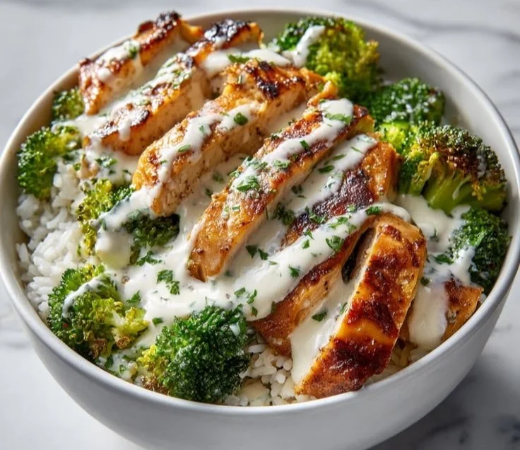 Chicken and broccoli bowl topped with creamy garlic sauce on a plate