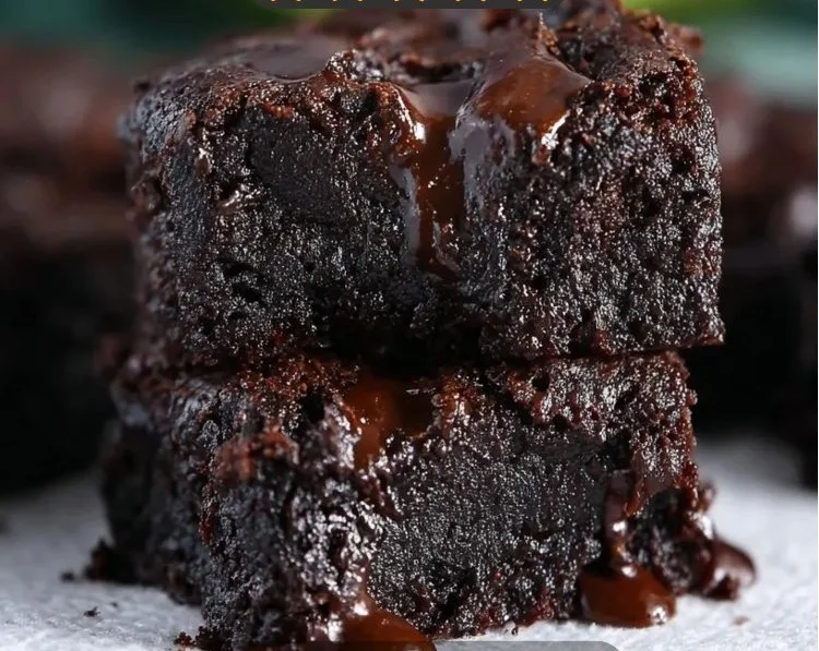 Delicious fudgy avocado brownies topped with chocolate drizzle on a white plate.