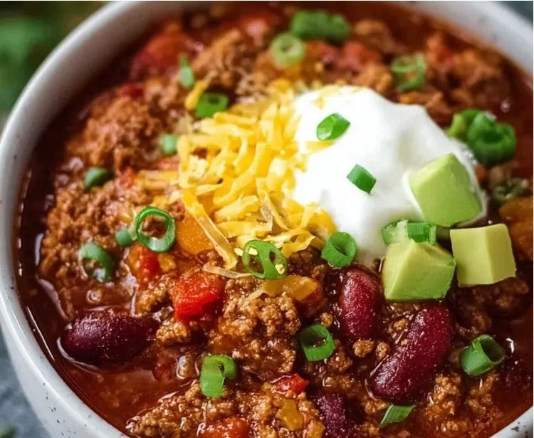 Bowl of hearty beef and bean chili topped with fresh herbs and spices